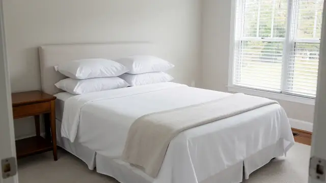 A freshly made bed with white sheets in a calm bedroom